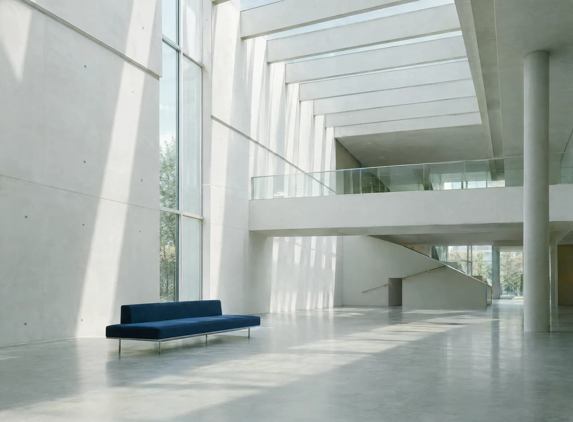 A light-filled modernist atrium with a single navy bench